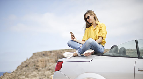 Girl texting on top of the car
